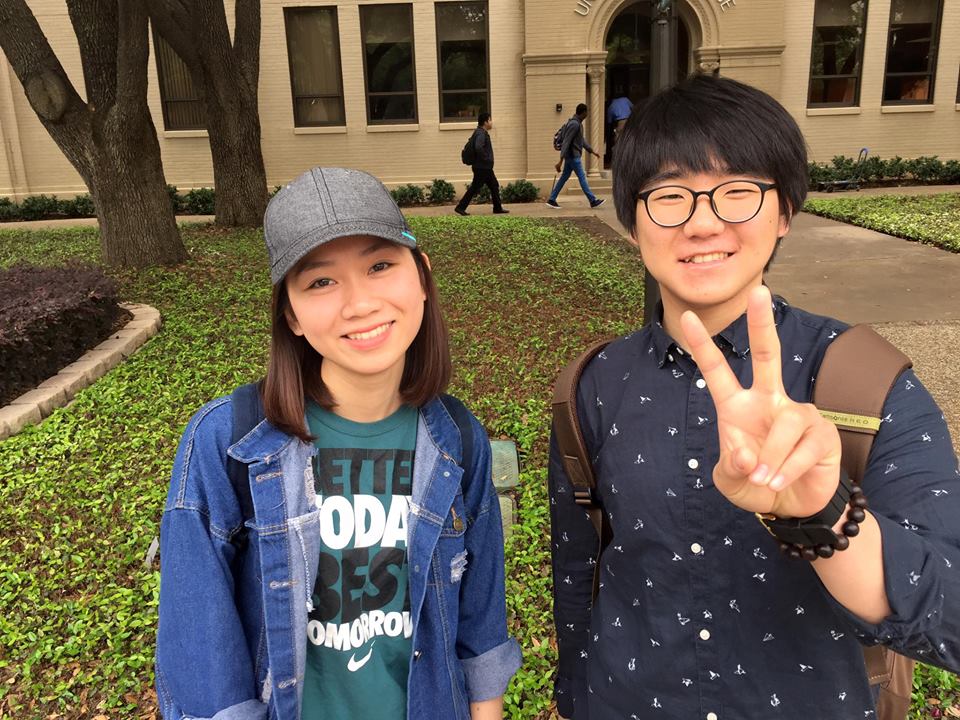 Two students on campus smiling and flashing peace sign