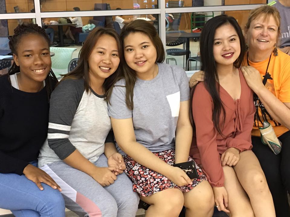 Students and staff on bench smiling at camera