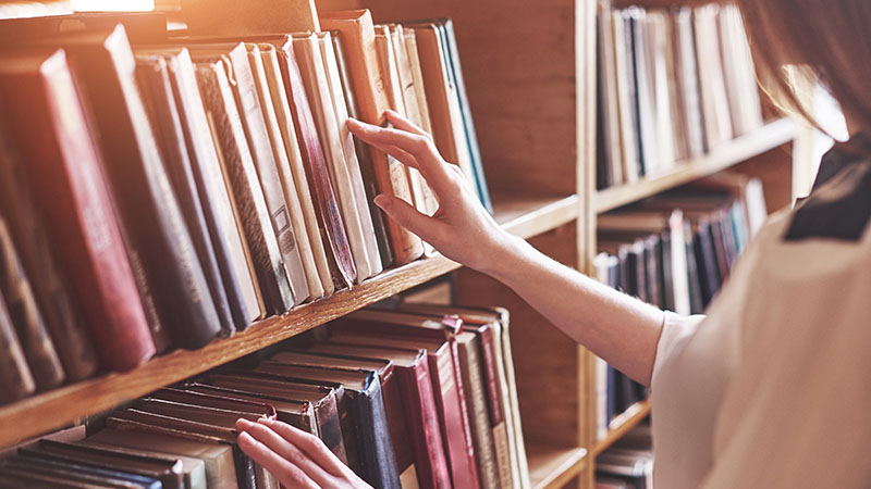 Woman reaching for book in library