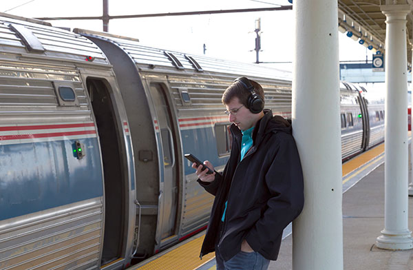 Man with headphones waiting to board AMTRAK train
